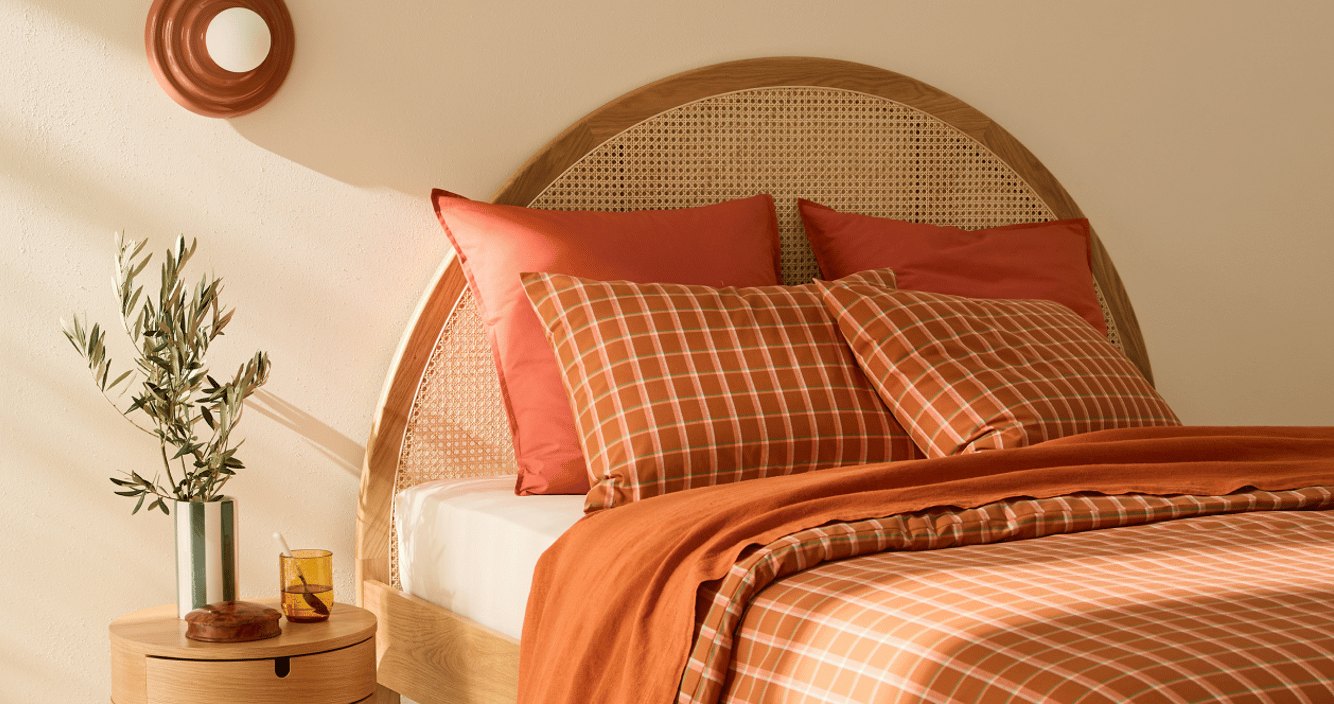Quarto com cabeceira em palhinha e roupa de cama em tons terra